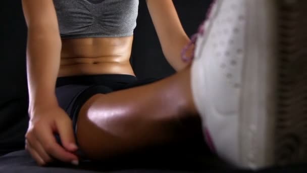 Close up of a young woman with sports body stretching against black background — Stock Video