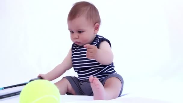 Menino feliz está brincando com raquete de tênis em um fundo branco — Vídeo de Stock