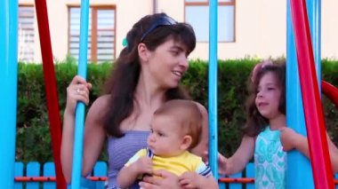 Anne ve küçük oğlu bir oyun alanı üzerinde sallanan