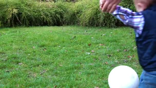 Petit garçon mignon jouant avec le ballon de football soutenu par sa mère — Video