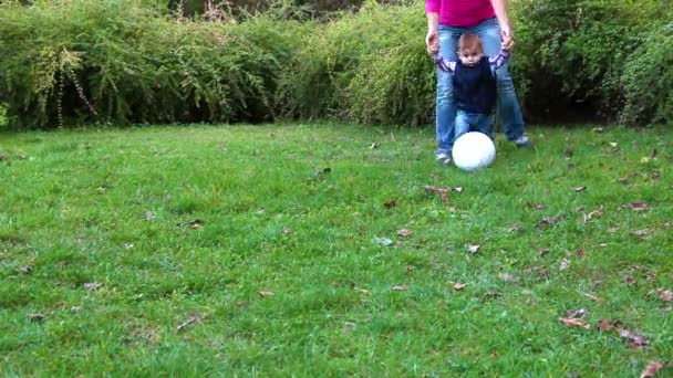 彼の母によってサポートされているサッカー ボールで遊ぶかわいい男の子 — ストック動画