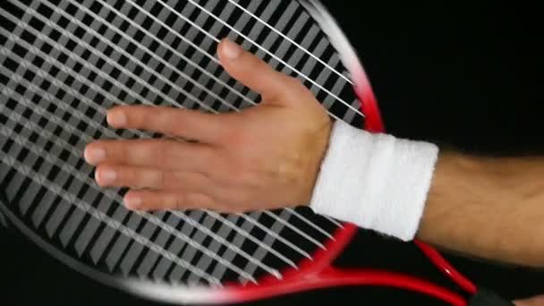 Movimiento lento de la mano de un jugador de tenis golpeando la red de su raqueta de tenis, fondo negro — Vídeos de Stock