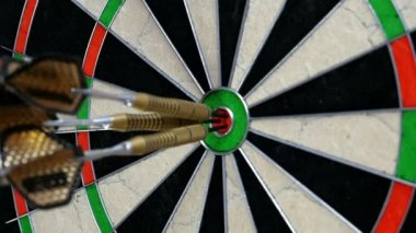 Ağır çekim üç Dart dart tahtası ve onları oyuncunun eli turnayı gözünden vurmak