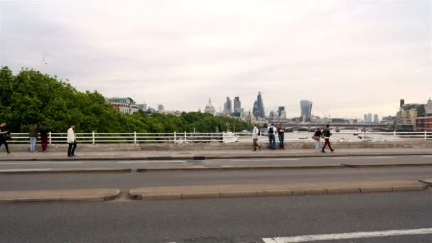 Tid förflutit av bussar, bilar och fotgängare på en av broarna över floden Themsen, London city, skyskrapor i bakgrunden — Stockvideo