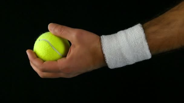 Slow motion of a tennis player's hand ready to toss the tennis ball before hitting it, black background — Stock Video