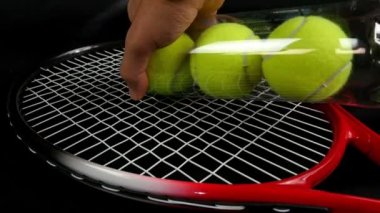 Üç yeni tenis topları kümesi tenis raketi üzerinde siyah arka plan üzerine koyarak el