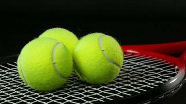 Mano masculina / femenina pone tres pelotas de tenis en una raqueta de tenis sobre un fondo negro — Vídeos de Stock