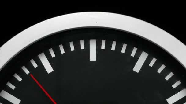 Primo piano di un orologio da parete nero isolato su sfondo nero. Passaggio della seconda mano rossa — Video Stock