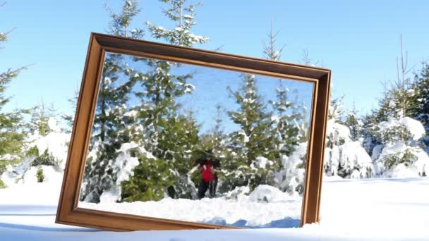 Mother and daughter playing in winter snow, frame in the foreground. The image in the frame is with oil paint effect — Stock Video