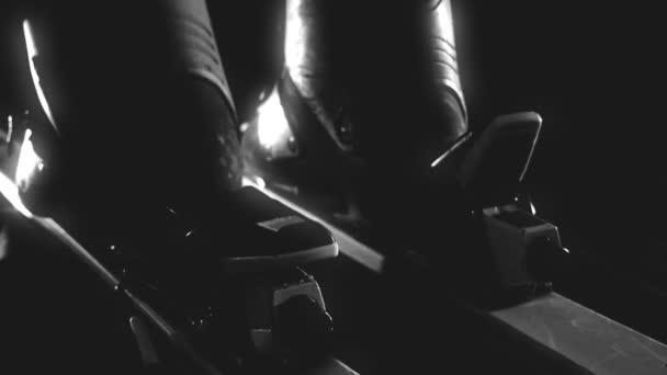 Skier attaching his ski boots, rear closing/opening of ski on black background, black and white video — Stock Video