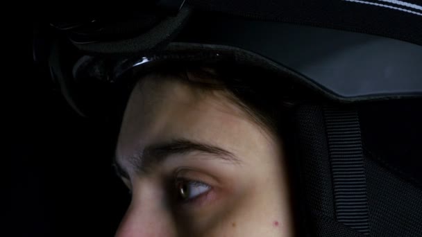 Skier/snowboarder woman putting her glasses on black background, close up — Stock Video