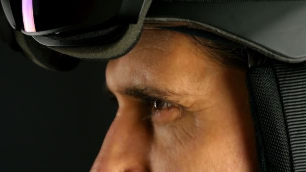 Skieur / snowboardeur mettant ses lunettes sur fond noir, gros plan 