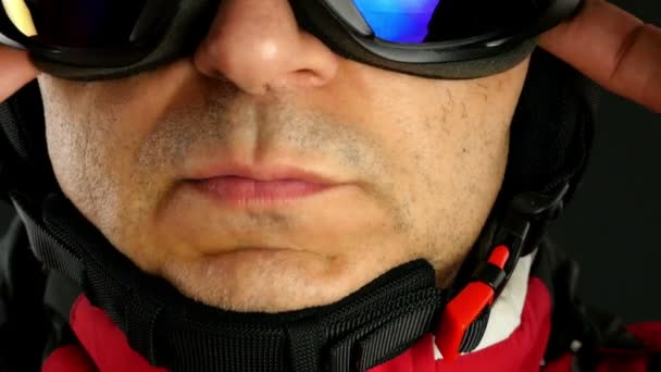 Esquiador / snowboarder abrocha su casco sobre fondo negro, de cerca — Vídeos de Stock