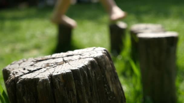 Barn balansera på stubbar i naturen, fötter bara — Stockvideo