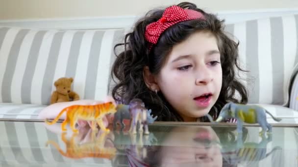 Κοντινό πλάνο της ένα χαριτωμένο κορίτσι παίζει με τα παιχνίδια-ζωάκια σε ένα τραπέζι, dolly — Αρχείο Βίντεο