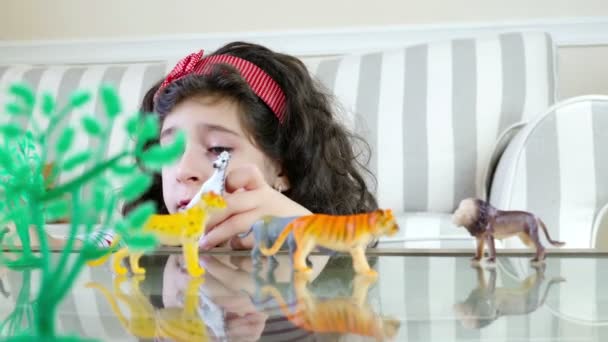 Gros plan d'une jolie fille jouant avec des jouets animaux sur une table, poupée — Video