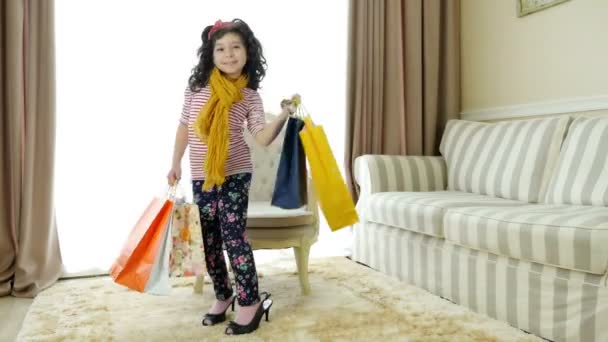 Χαριτωμένο μικρό κορίτσι σε ψηλά τακούνια και με σακούλες αγορών που μιμούνται τη μητέρα της — Αρχείο Βίντεο