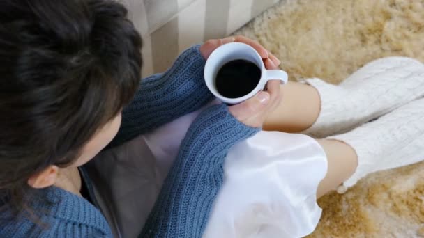 Woman in warm vest sipping her hot drink / coffee / tea, camera close up in front of model — Stockvideo