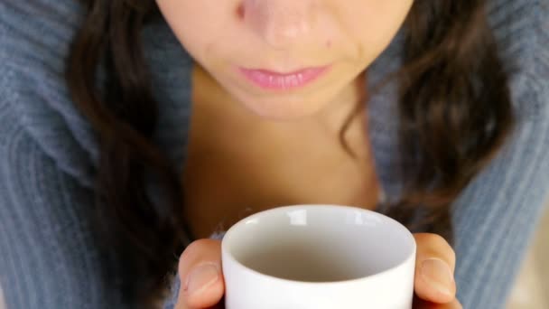 Mujer en chaleco caliente sorbiendo su bebida caliente / café / té, cámara de cerca delante de la modelo — Vídeos de Stock