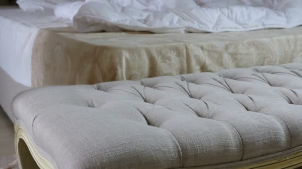 Nő erotikus hálóruhaként dob egy pouf előtt egy vetetlen ágy, egy hálószoba — Stock videók
