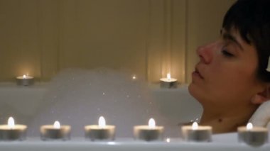 Güzel kadın rahatlatıcı mumlar çevrili bir küvet içinde