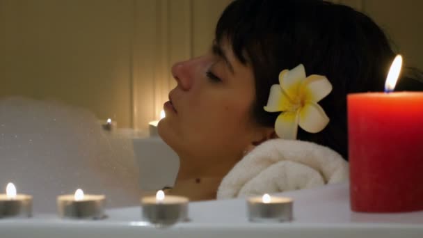Mooie vrouw ontspannen in een badkuip, omringd door kaarsen — Stockvideo