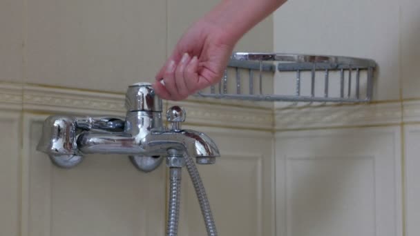 Женская рука управляет водопроводной водой в ванной комнате — стоковое видео