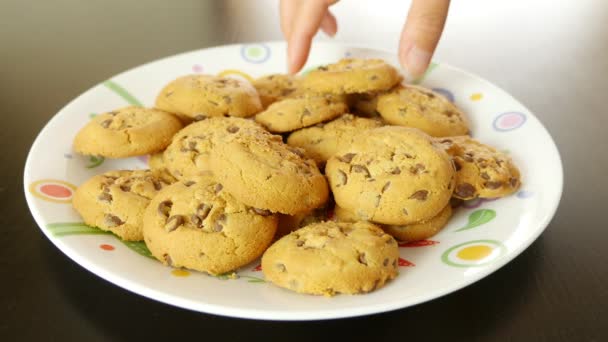 Hand tar en cookie från en platta på ett bord, den andra försvinner en efter en — Stockvideo