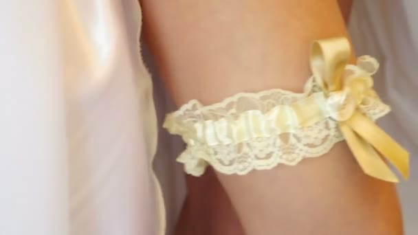Bride with wedding dress putting on a garter — Stock Video