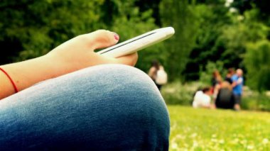 Bir parkta oturan cep telefonu kullanarak kadın yakın, eller sadece