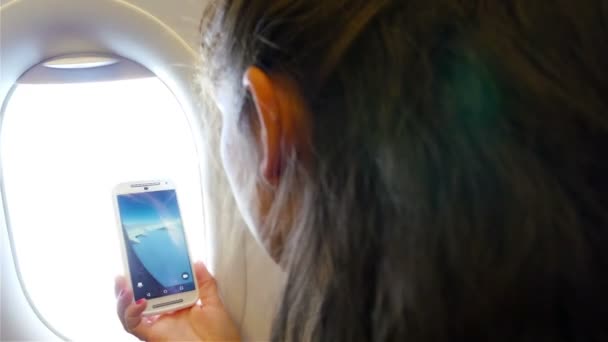 Mujer sentada junto a la ventana del avión tomando fotos con su teléfono inteligente — Vídeo de stock