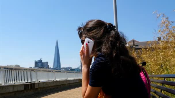 Mujer joven enviando un sms con un teléfono móvil con el puente de la Torre de Londres y fragmento en el fondo, cerca de las manos — Vídeos de Stock