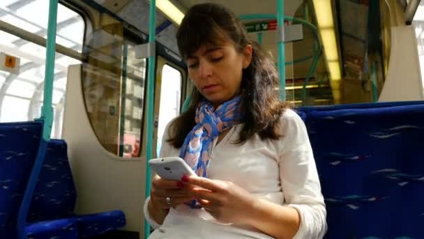 Mulher usando telefone inteligente enquanto viaja em um trem ferroviário em Londres — Vídeo de Stock