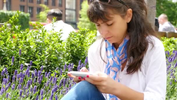 Mulher usando telefone inteligente enquanto sentado em um parque em Londres — Vídeo de Stock