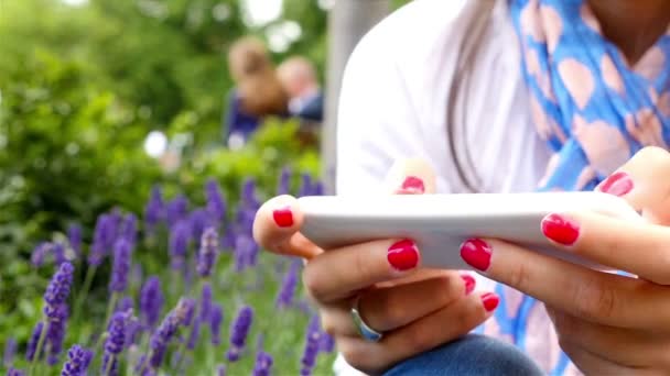 Femme utilisant un téléphone intelligent alors qu'elle était assise dans un parc à Londres, mains seulement 