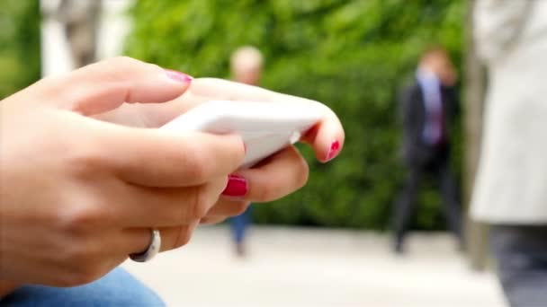 Femme utilisant un téléphone intelligent alors qu'elle était assise dans un parc à Londres, mains seulement — Video