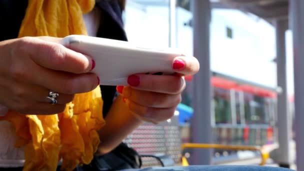 Mulher usando telefone inteligente esperando em uma estação ferroviária em Londres — Vídeo de Stock