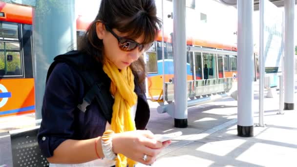 Mulher usando telefone inteligente esperando em uma estação ferroviária em Londres — Vídeo de Stock