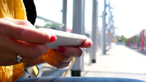 Mujer usando teléfono inteligente esperando en una estación de tren en Londres — Vídeos de Stock