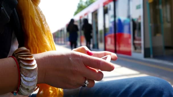 Mujer usando teléfono inteligente esperando en una estación de tren en Londres — Vídeo de stock