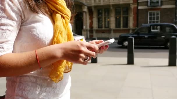 Femme utilisant un téléphone intelligent dans une rue de Londres, véhicules en arrière-plan, mains seulement — Video