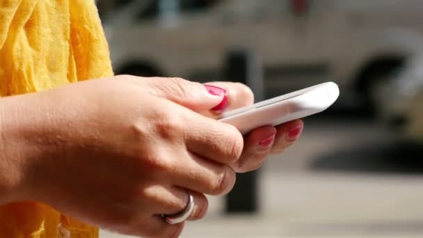 Mujer usando teléfono inteligente en una calle de Londres, vehículos en el fondo, manos solamente — Vídeo de stock