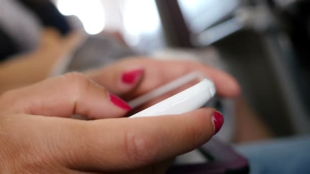 Mujer usando un teléfono inteligente mientras viaja en un avión — Vídeos de Stock