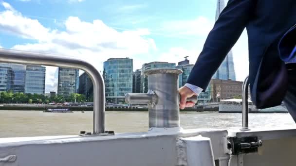 Vind blåser kostymen av en affärsman på en båt på floden Thames, London, Tower Bridge på baksidan — Stockvideo