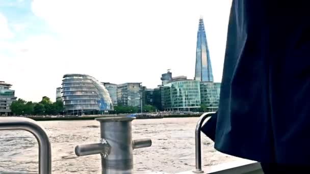 Vento che soffia la tuta di un uomo d'affari su una barca sul Tamigi, Londra, Tower bridge sul retro — Video Stock