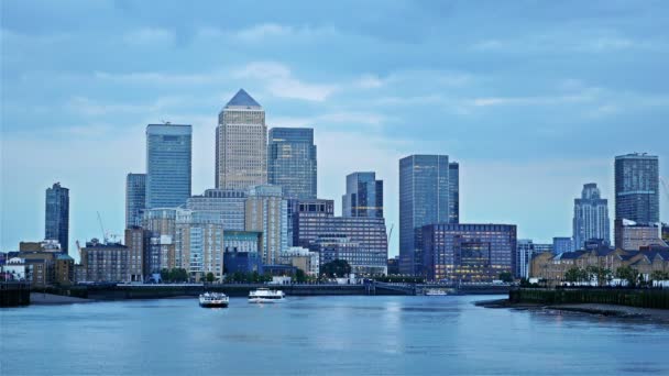 Barcos flutuando no rio Tamisa ao pôr do sol, Londres, centro de negócios Canary Wharf no fundo — Vídeo de Stock