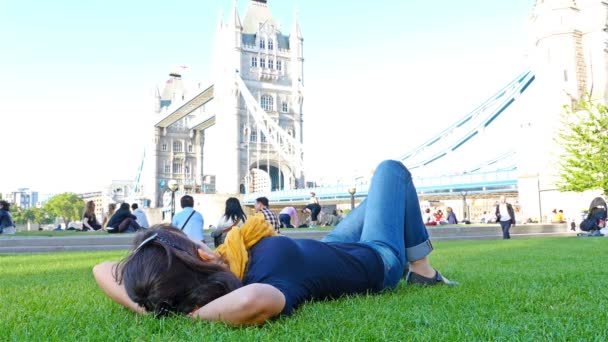 REINO UNIDO, LONDRES - 18 DE JUNIO DE 2015: Personas relajadas en un parque cerca de Tower Bridge, Londres — Vídeo de stock