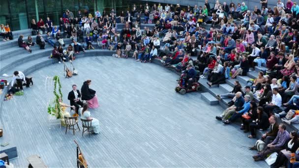 REINO UNIDO, LONDRES - 12 DE JUNHO DE 2015: Estilo de vida londrino. Pessoas assistindo teatro no Scoop, Londres - o anfiteatro ao ar livre perto de Tower Bridge — Vídeo de Stock