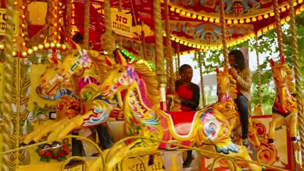 REINO UNIDO, LONDRES - 16 DE JUNHO DE 2015: Estilo de vida londrino. Pessoas divertidas em um carrossel em movimento com cavalos de madeira coloridos, Londres, Reino Unido — Vídeo de Stock