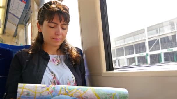 Mulher turística segurando um mapa de Londres enquanto viaja em um trem ferroviário — Vídeo de Stock